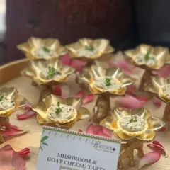 Elegant mushroom and goat cheese tarts served in beautiful golden lotus-shaped cups, finished with a dusting of parmesan.
