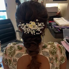 A soft and romantic braided hairstyle, decorated with baby's breath and small daisies. This look is perfect for a Mehendi or Sangeet event.