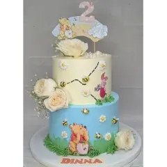 A tall, two-tier Winnie the Pooh cake perfect for a second birthday. This choco-vanilla cake features Pooh and his friends in the Hundred Acre Wood, decorated with fresh flowers for a soft, storybook feel.