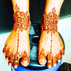 A lovely floral mehndi design for the feet. The pattern extends from the ankle to the toes, resembling a delicate piece of foot jewelry. The stain is a beautiful deep red.