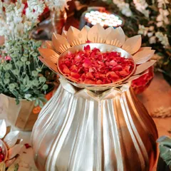 A beautiful brass lotus-shaped urn filled with fresh rose petals, a key element in our traditional Indian event decor.