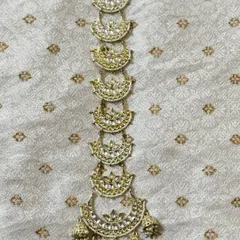 A delicate hair choti accessory with half-moon Kundan pieces and pearl detailing. This rental piece adds elegance to your hairstyle.