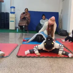 Stretching is fun, especially with friends. Here, our youngest students work on their forward bends and straddle stretches on colorful mats, learning the basics of flexibility in a group setting.