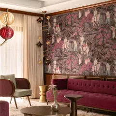 This living room is an exploration of maximalism, where a deep magenta velvet sofa is set against a rich, narrative wallpaper. We designed custom sculptural coffee tables and armchairs to create a layered, collected feel that is both bold and inviting.