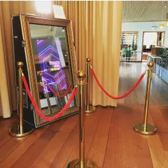 Our elegant Mirror Selfie Booth is set up and ready for an event. The full-length mirror features an interactive touchscreen with animations that guide guests, while the premium gold stanchions and red rope add a touch of VIP class.
