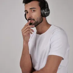 A lifestyle shot of a model wearing black headphones against a clean studio background. Using a model helps demonstrate the product's scale and how it looks when worn.