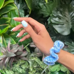 A beautiful light blue velvet scrunchie, shown here on the wrist. The velvet yarn has a lovely sheen and is incredibly soft against the skin.