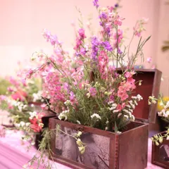 A charming and rustic floral arrangement. Wildflowers in shades of pink and purple are placed in a vintage wooden box, adding a personal and nostalgic touch to the decor.