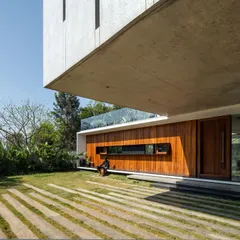 A dramatic view of the Long House, where a massive concrete cantilever provides shade and architectural presence over a timber-clad lower level.