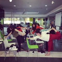 Using chairs for support in a balancing pose. This makes yoga accessible to everyone in the office, regardless of their flexibility or experience level.