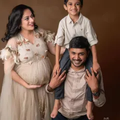 A heartwarming family photo celebrating the new arrival. The mom-to-be is radiant in our beige embellished gown, surrounded by her loving family.