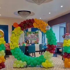 A circular balloon photo booth frame designed for a jungle-themed birthday. The setup includes colorful balloons and pillars topped with monkey and lion foil balloons for fun photo opportunities.