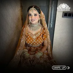 A full view of a happy bride in her beautiful orange lehenga. The makeup is bright and radiant, perfect for a day wedding or Anand Karaj ceremony.