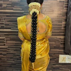 A detailed look at a traditional South Indian bridal braid, intricately woven and adorned with pearls and a beautiful hair accessory.