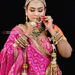 Adjusting the nath, a classic bridal moment. The makeup, with its warm tones and sharp contour, ensures the bride looks flawless from every angle.