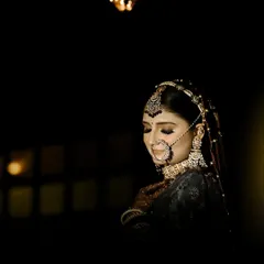 A dramatic low-light portrait focusing on the bride's stunning jewelry and serene expression. This style of photography adds a touch of glamour and mystery to the bridal album.