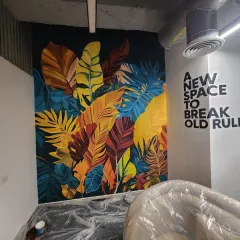 The completed botanical mural next to a typography piece that reads "A NEW SPACE TO BREAK OLD RULES." This combination of art and text creates a powerful, motivating atmosphere in the office.