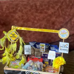 This "What will Baby Bee?" themed hamper is a fun choice for a baby shower. The crate is loaded with chocolates and snacks, and decorated with yellow feathers and bee-themed signs for a unique touch.