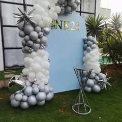 An alternate angle of the modern outdoor balloon arch decoration. This view shows the depth of the silver and white balloon arrangement against the custom blue backdrop.