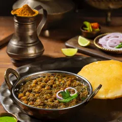 Chole Bhature, a classic North Indian dish, styled with fresh ingredients for Rakesh Masala. The dark, moody lighting enhances the rich colors of the curry.