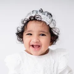 The most infectious giggle. Sitter sessions are full of laughter, and my goal is to capture that authentic happiness. This portrait in a simple white outfit keeps the focus entirely on her joyful expression.