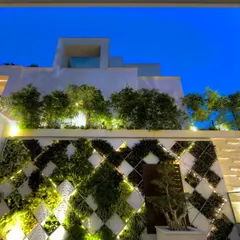 This exterior facade showcases a geometric living wall illuminated at night. The design uses a diamond-patterned framework with integrated lighting to create a dramatic visual effect, turning the building's exterior into a landmark after dark.