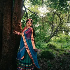 A full-length portrait capturing the grace of Radha amidst a verdant forest, her colorful attire standing out against the natural backdrop.