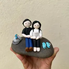 A simple, sweet moment captured in clay. This miniature features a couple sitting together on a stone, perfect as a keepsake to celebrate a relationship or a special memory.
