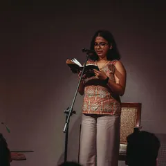 A poet lost in her words during a performance. Our stage is an intimate space, creating a powerful connection between the artist and the audience.