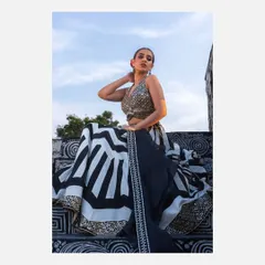 A striking outdoor shot of a model in a modern black and white geometric lehenga by designer Vandana Sethi. The low angle and sky in the background create a powerful and dramatic fashion statement.