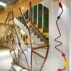 The staircase at the AMG office is a key architectural feature. The side wall is brought to life with a rhythmic composition of backlit maple wood hexagons, which also discreetly conceals electrical fixtures, perfectly marrying function with aesthetic form.