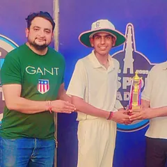 A young player in his cricket whites proudly accepts a trophy, a symbol of his dedication and achievement.
