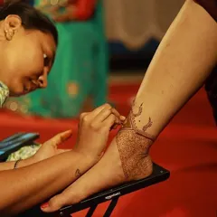 This is me in my element, applying an intricate ankle and foot design. I use a comfortable, ergonomic setup to ensure I can focus on the details and provide the best experience for my client.