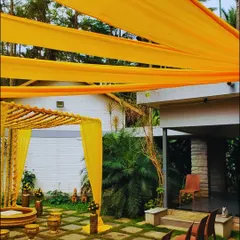 A classic Haldi ceremony setup featuring a bright yellow draped mandap, hanging marigolds, and traditional brass urlis for the ritual.