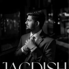 A dapper black and white portrait of the groom, Jagdish, adjusting his tie. This shot captures his suave and confident look for the reception.