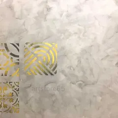 The combination of a soft, smoky grey texture and sharp, metallic gold stencils provides a beautiful contrast. This technique allows for intricate designs on a subtle, elegant background.