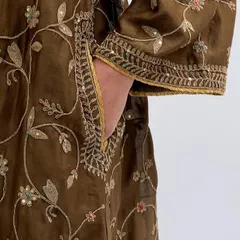 Embroidery that speaks the language of grace. A detailed shot of the sleeve and pocket of an earthy brown kurta, covered in delicate floral vine embroidery.