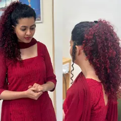 A different view of the fiery red curls, styled in a high ponytail to showcase the volume and the beautiful color gradient.