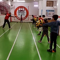 A coach demonstrates the proper way to hold and throw a ball, with the kids watching intently. We believe in leading by example and breaking down skills into easy-to-understand steps.
