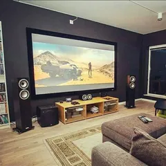 This setup shows how a high-performance system can be integrated into a living room. We installed a large fixed-frame screen and paired it with floor-standing tower speakers and a dedicated subwoofer. The result is a powerful audio-visual experience that coexists with a comfortable, everyday living space.
