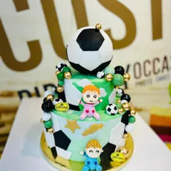 A fun 4kg two-tiered football theme cake with a large fondant soccer ball on top.