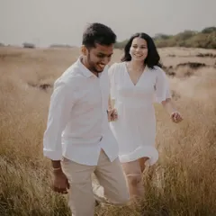 Capturing a fun, candid moment as the couple runs through a field of tall grass near Pune. Their coordinated white outfits and genuine smiles make this a lighthearted and joyful pre-wedding photo.