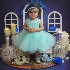 A vision in blue! This sweet little girl is all smiles in our dreamy blue-themed studio setup, complete with white window props, candles, and flowers.