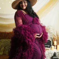 A gentle, loving pose in our boho-themed setup. The mom-to-be cradles her bump, surrounded by soft textures and warm candlelight, creating a cozy and artistic portrait.