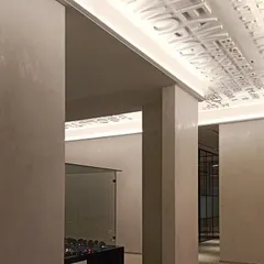 In this office space, cove lighting is used in a creative way to highlight the three-dimensional motivational text on the ceiling. This detail turns a simple transitional area into an inspiring brand statement, showcasing how light can interact with architectural features.