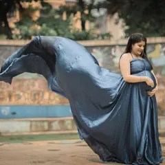 The deep, satin-finish blue of this gown creates a sense of elegance and royalty. The tossing train effect adds a dynamic and artistic element to your maternity portraits.
