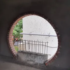 This is a work-in-progress shot of a circular window framed with wire-cut bricks. The design includes a built-in seat, transforming a simple opening into a cozy nook and a unique visual feature that connects the traditional brickwork with the contemporary interior.