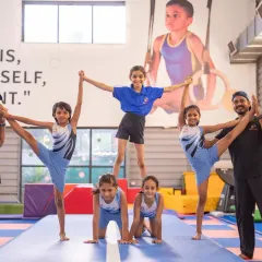 Teamwork makes the dream work. Here, our gymnasts and coaches come together to create a human pyramid, showcasing balance, strength, and the supportive community we build in our kids' fitness classes.