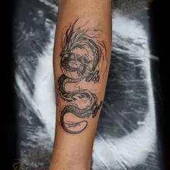The final result of a cover-up on the forearm, featuring a dynamic, sketchy-style dragon tattoo. The dark ink and flowing lines were strategically placed to hide a very faded older piece underneath.
