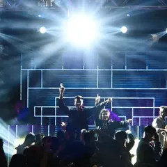 A high-energy moment on stage, captured with dramatic backlighting that creates a powerful silhouette effect.